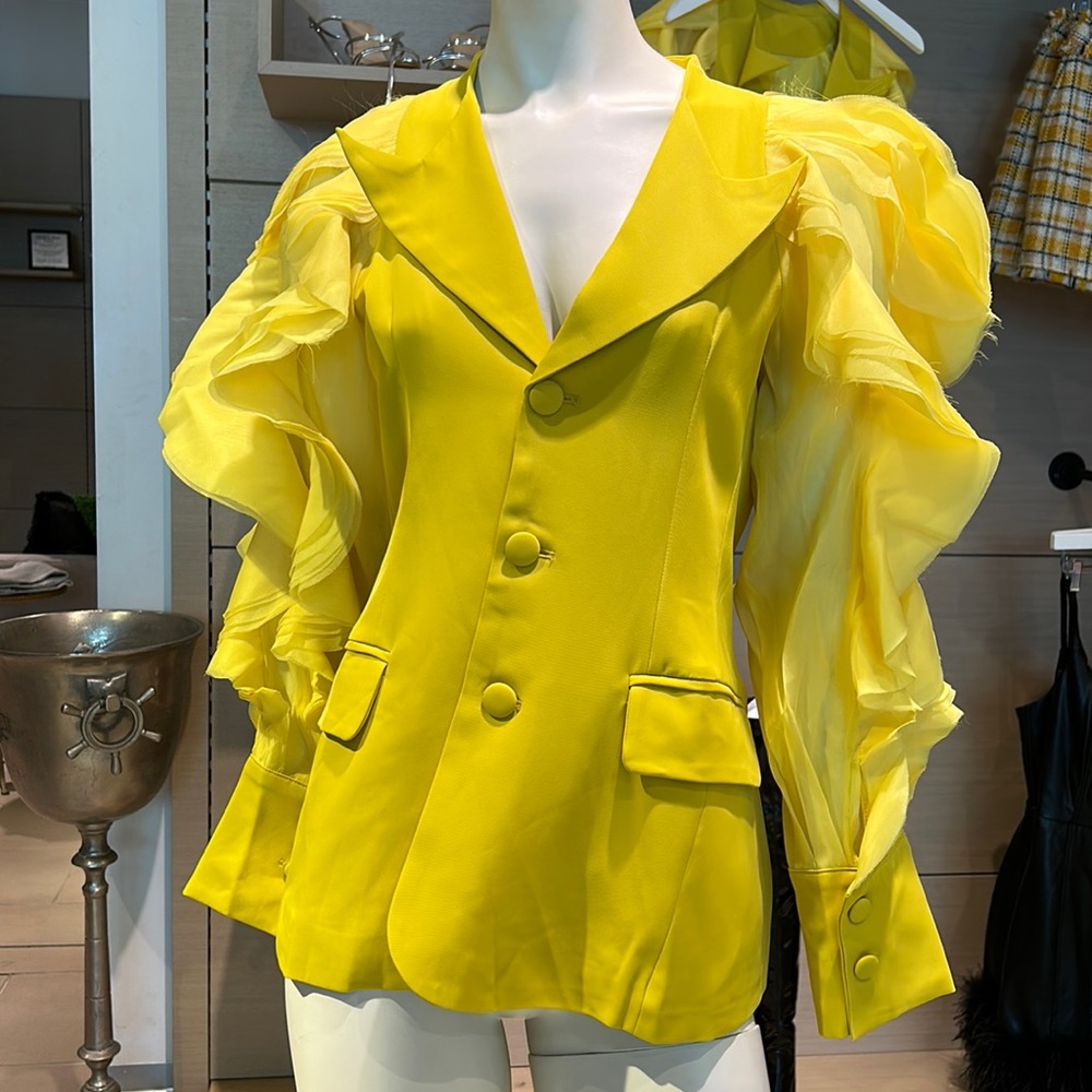 Tailored yellow blazer with ruffled sleeves.